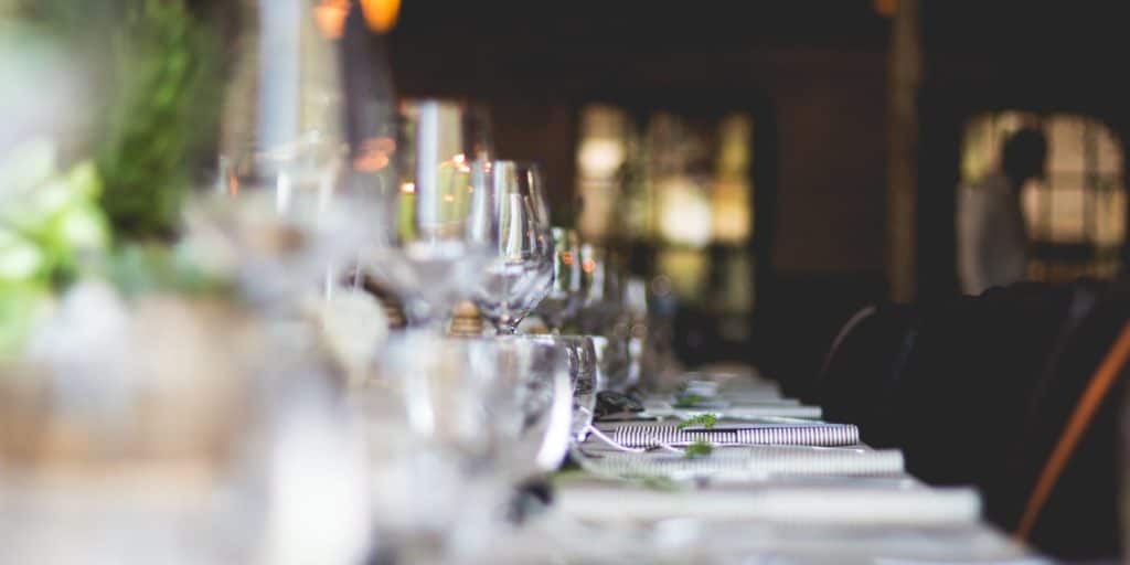 Zu Hause ist ein langer Tisch mit Gläsern und Tellern gedeckt.