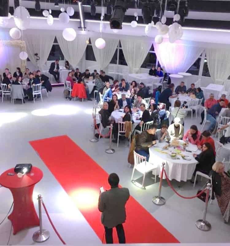 Ein großer Raum mit Tischen und Stühlen und einem roten Teppich.