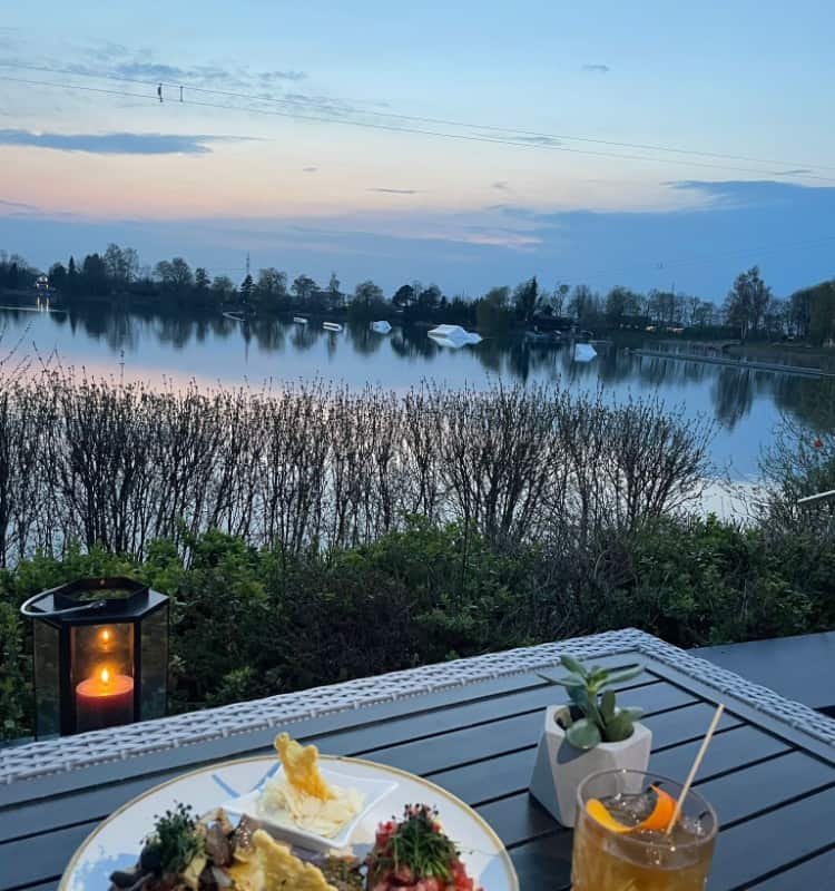 Ein Teller mit Essen auf einem Tisch neben einem See.